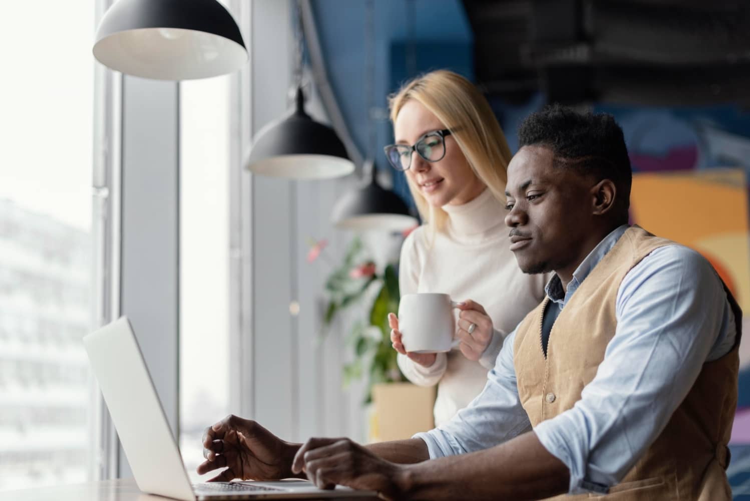 colleagues looking at a laptop in a brightly lit modern office